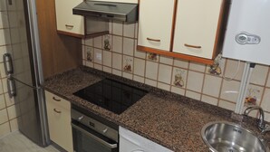 Una cocina con refrigerador, horno, microondas y pileta de acero inoxidable.