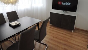 Un salón de conferencias con una pantalla plana que muestra el logo de YouTube, una lámpara de araña moderna y suelo de madera.