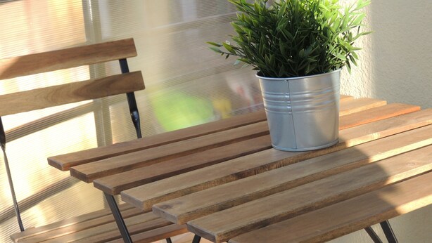 Una mesa de madera con una olla de metal que contiene una planta verde.