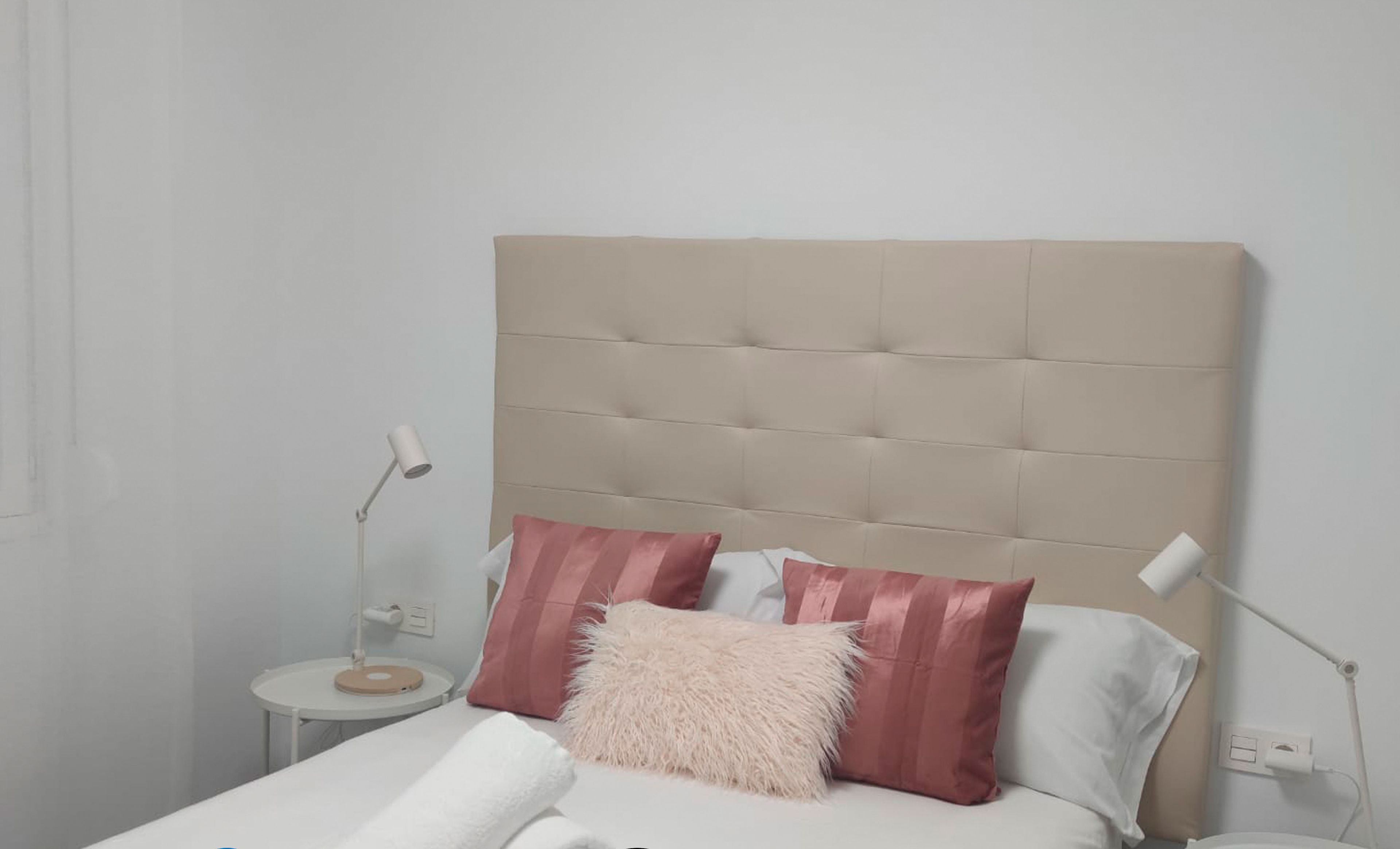 Quarto moderno com cabeceira estofada, roupa de cama branca e almofadas rosa e brancas. Inclui estacionamento gratuito, serviços de localização, Wi-Fi, controlo de desinfeção O3 e uma conta Netflix gratuita.