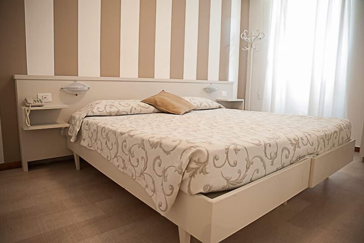 A bedroom with a bed, nightstands, a lamp, and a window with curtains.