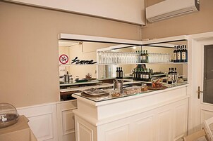 Un'area bar con una vetrina in vetro, scaffali con bottiglie e un cartello con su scritto 'No Smoking'.