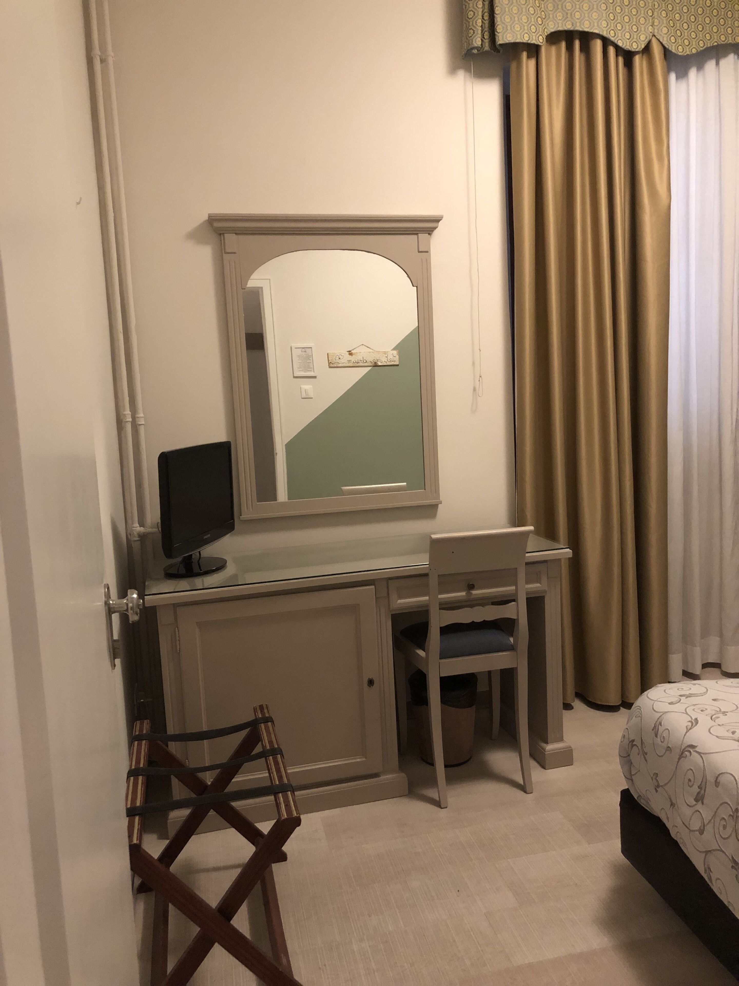 A hotel room with a desk, chair, and a bed.