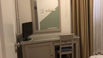 A hotel room with a desk, chair, and a bed.