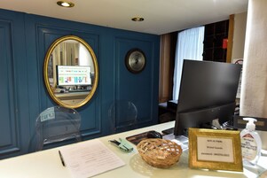 Una reception con scrivania, computer, specchio, orologio e segnale che indica accesso WiFi per gli ospiti.