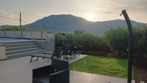 Una terraza en la azotea con piscina, mobiliario exterior y vistas a montañas.