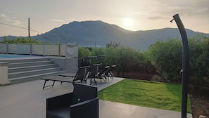 A rooftop terrace with a pool, outdoor seating, and a view of mountains.