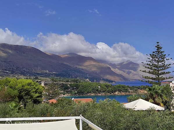 A coastal landscape with mountains, a body of water, and a white tent. - Villa Corallo - Scopello Guidaloca Bay (Castellammare del Golfo)