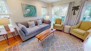 Ein Wohnzimmer mit grauem Sofa, gemusterten Kissen, einem Holztisch und einem Teppich mit Muster.