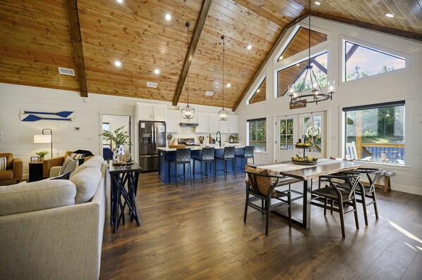 A spacious kitchen with a high ceiling, wooden beams, and large windows.