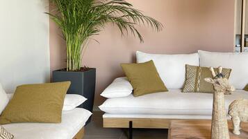 A modern living room with a sofa set, a large potted plant, and a wooden coffee table.