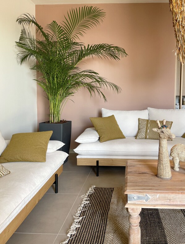 A modern living room with a sofa set, a large potted plant, and a wooden coffee table. - The Nest Resort (Hersonissos)