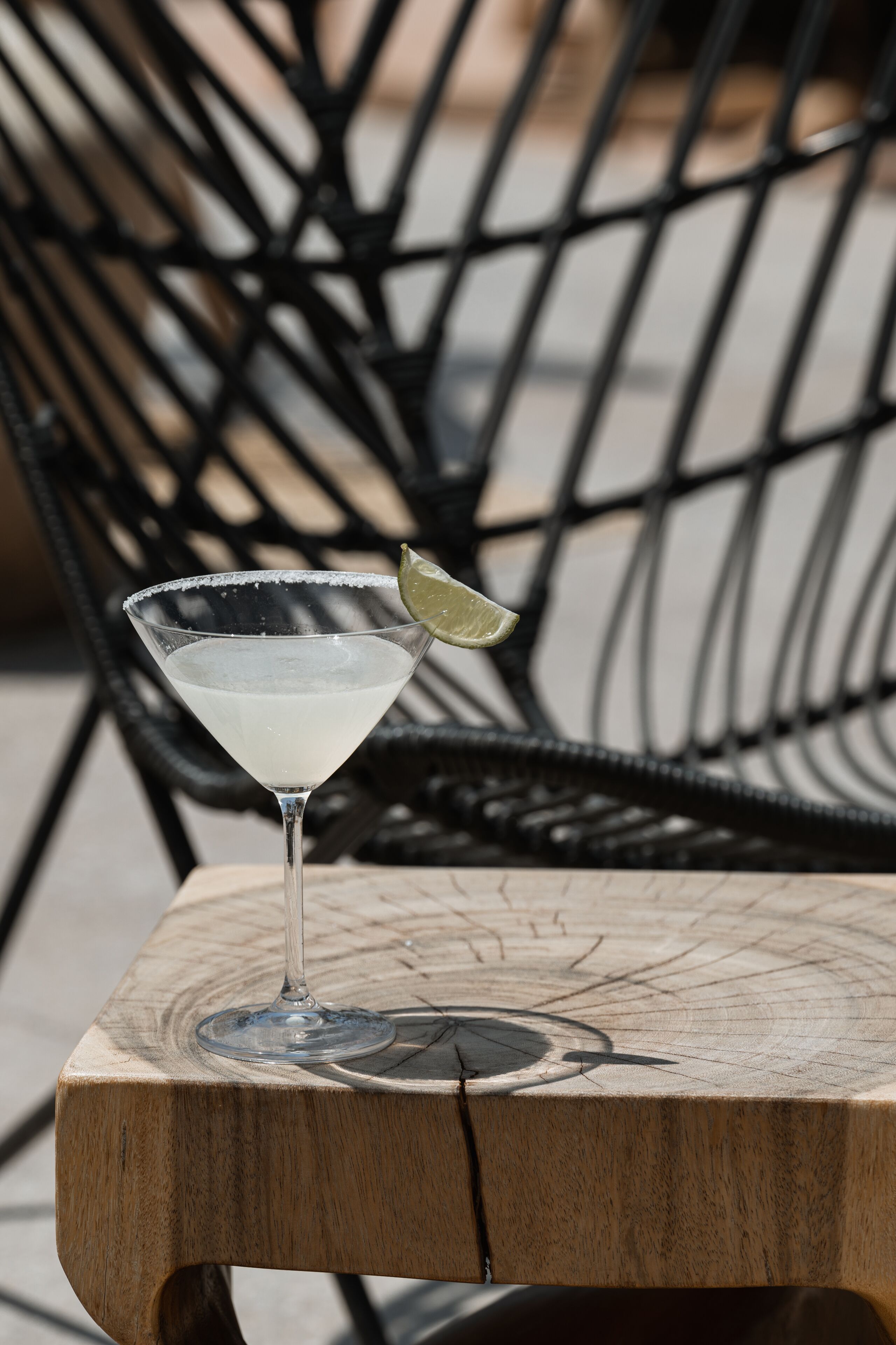 Een martini glas met een limoenpartje op een houten tafel.