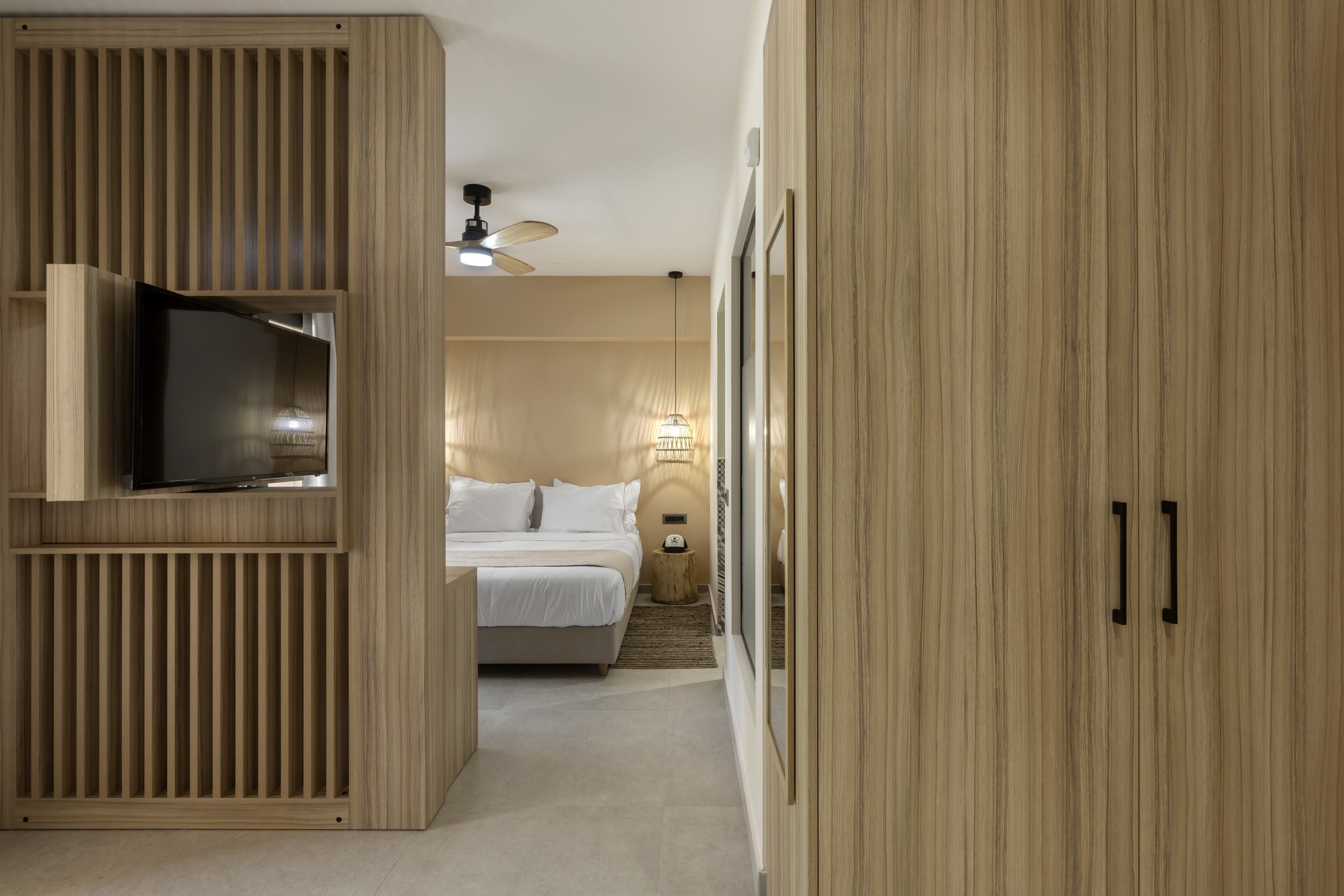 Ein Schlafzimmer mit einem Bett, einem Fernseher auf einem Holzschrank, einem Deckenventilator und einem Nachttisch mit einer Lampe.