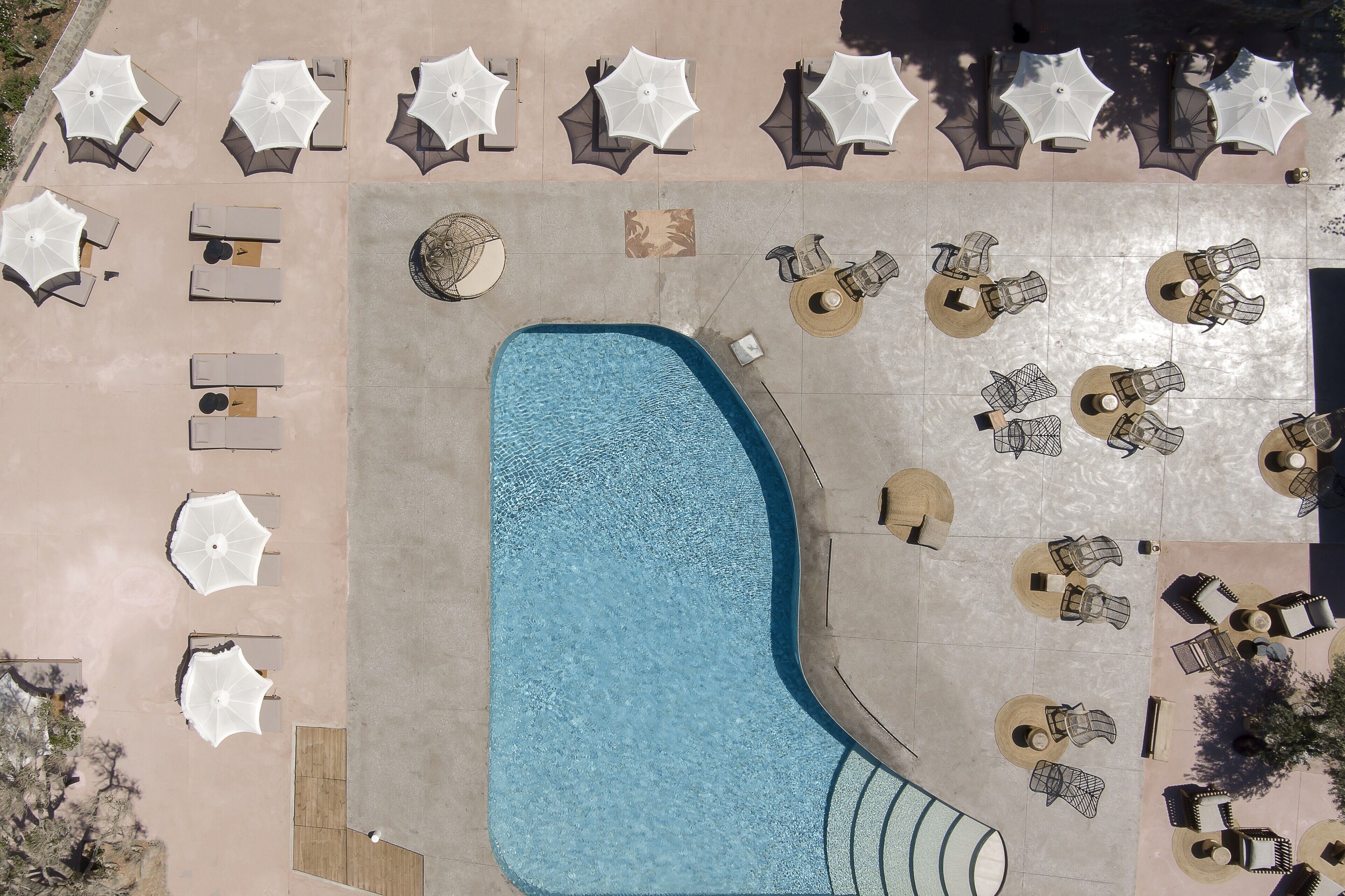 An aerial view of a pool area with lounge chairs and umbrellas arranged around the pool.