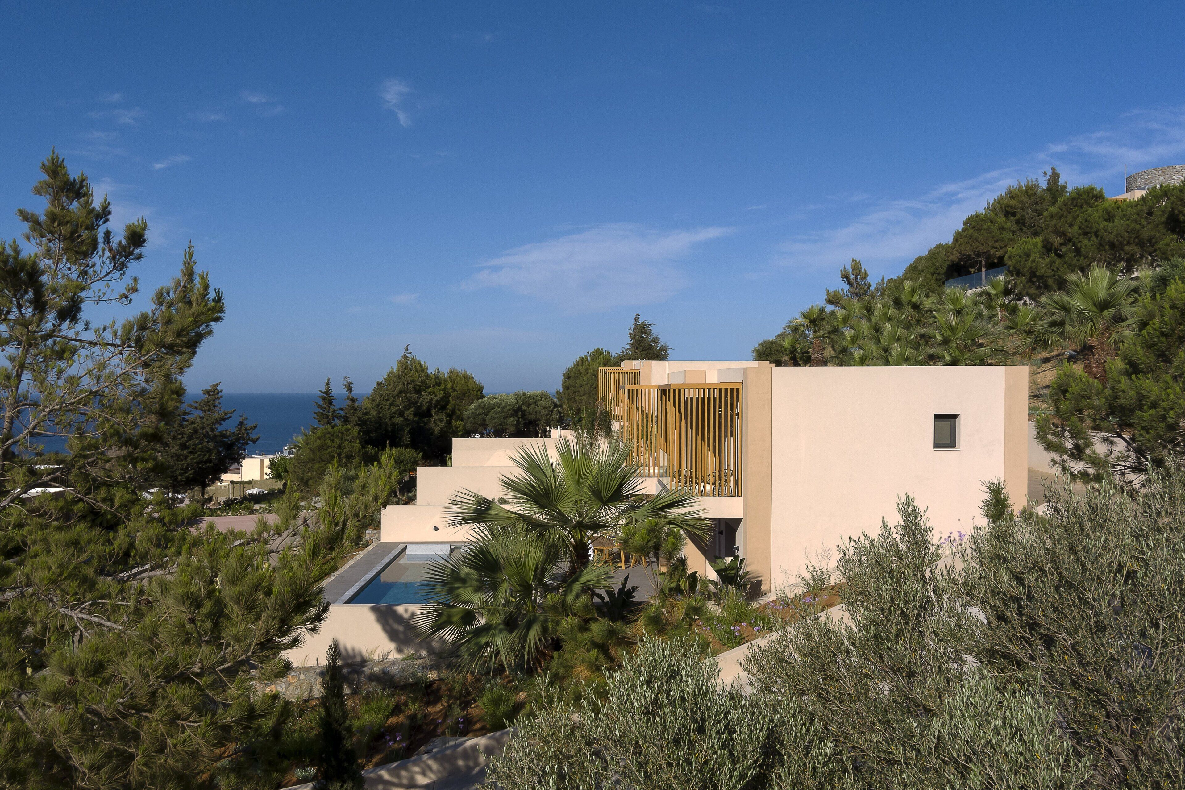 Una villa moderna con piscina, rodeada de exuberante vegetación y con vistas al mar.