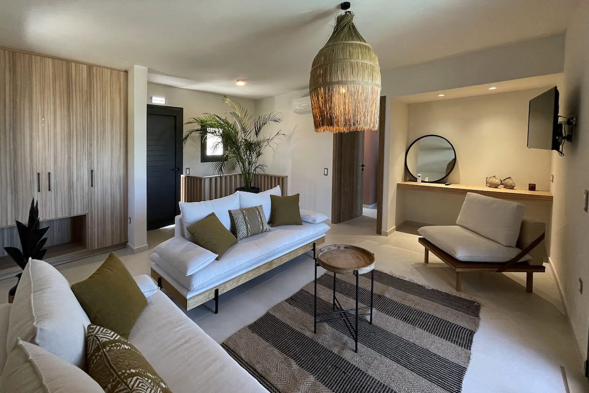 A modern living room with a sofa, armchair, and a hanging light fixture.