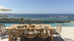 A dining table with wicker chairs and a view of the sea.