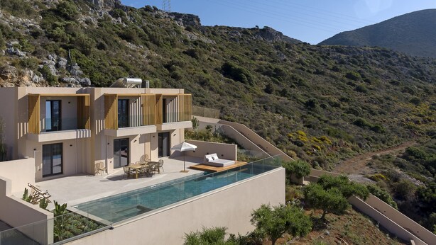 A modern house with a rooftop infinity pool, a terrace with seating, and a view of a mountainous landscape.