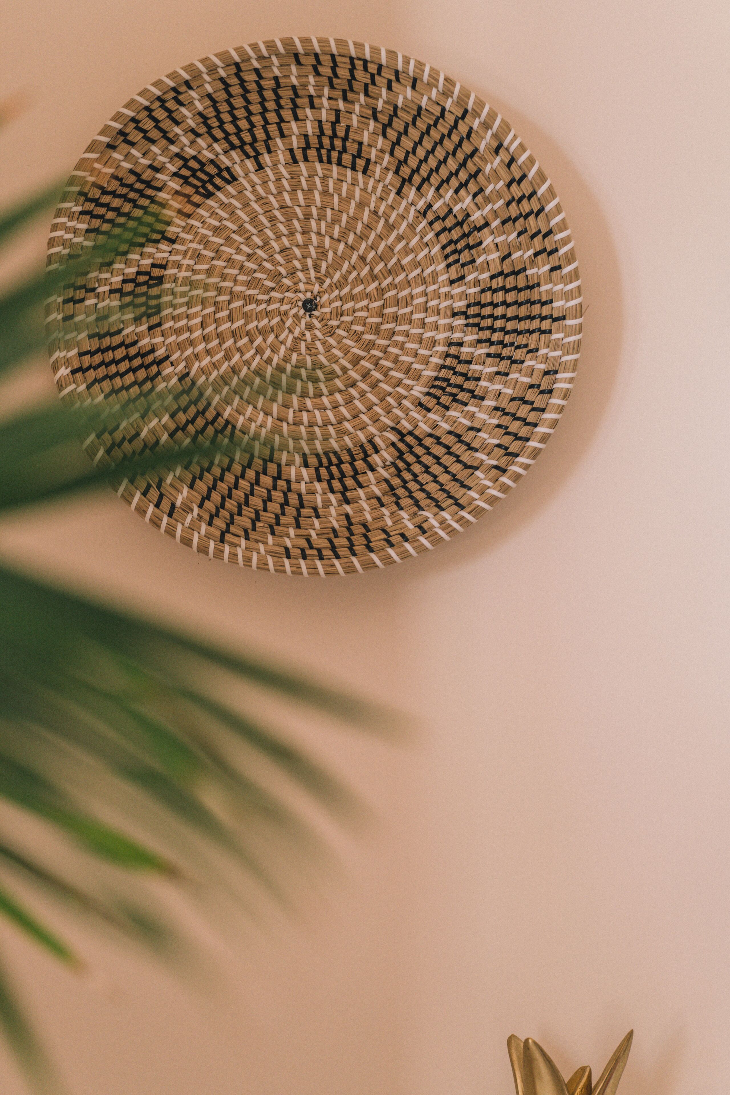 A circular woven wall hanging with a central knot, mounted on a plain wall.
