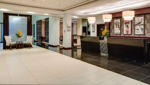 A hotel lobby with a reception desk, seating area, and decorative elements. - Alliance by Eagles (Sekondi-Takoradi)