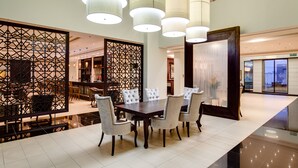 A spacious dining area with a large table and chairs, decorative wall panels, and hanging pendant lights. - Alliance by Eagles (Sekondi-Takoradi)