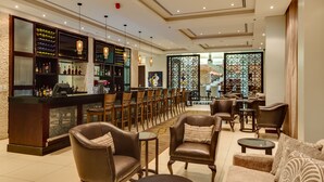 A bar area with leather chairs, a counter with bottles, and a view of the interior. - Alliance by Eagles (Sekondi-Takoradi)