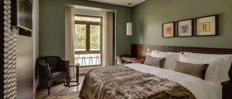 Un dormitorio con una cama grande, una silla, un escritorio y una ventana.