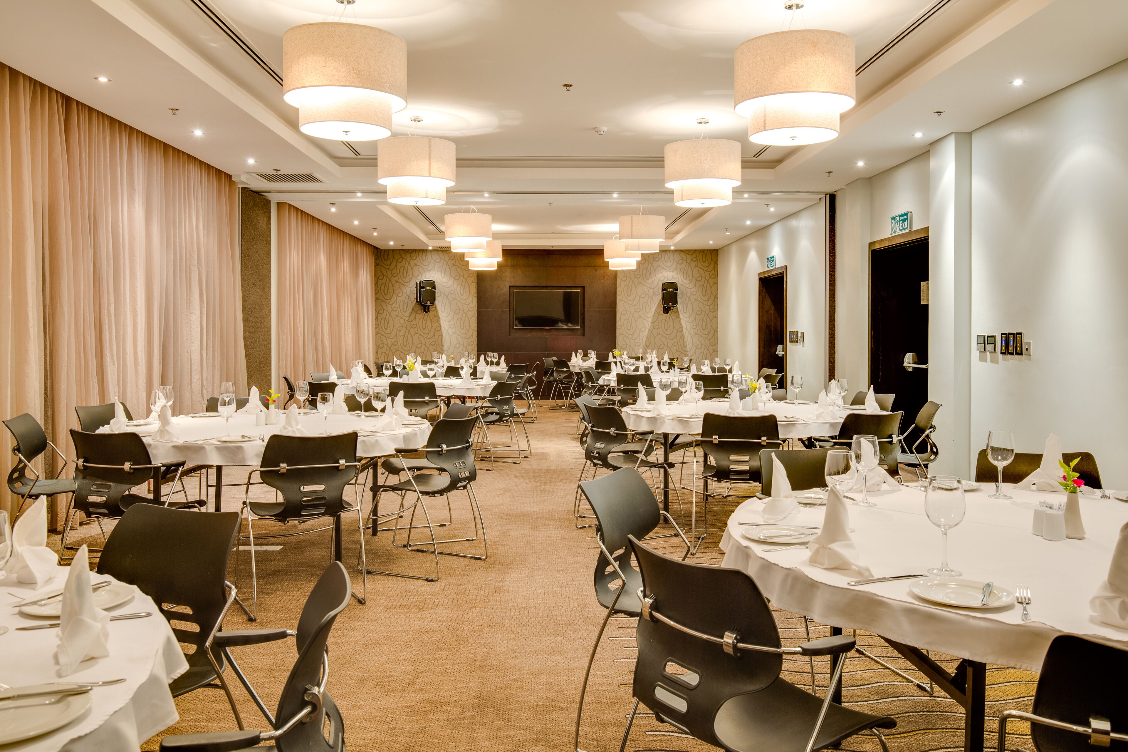A banquet hall with multiple round tables set for dining, equipped with chairs and table settings.