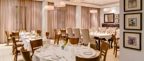 A dining area with round tables, chairs, and hanging light fixtures.