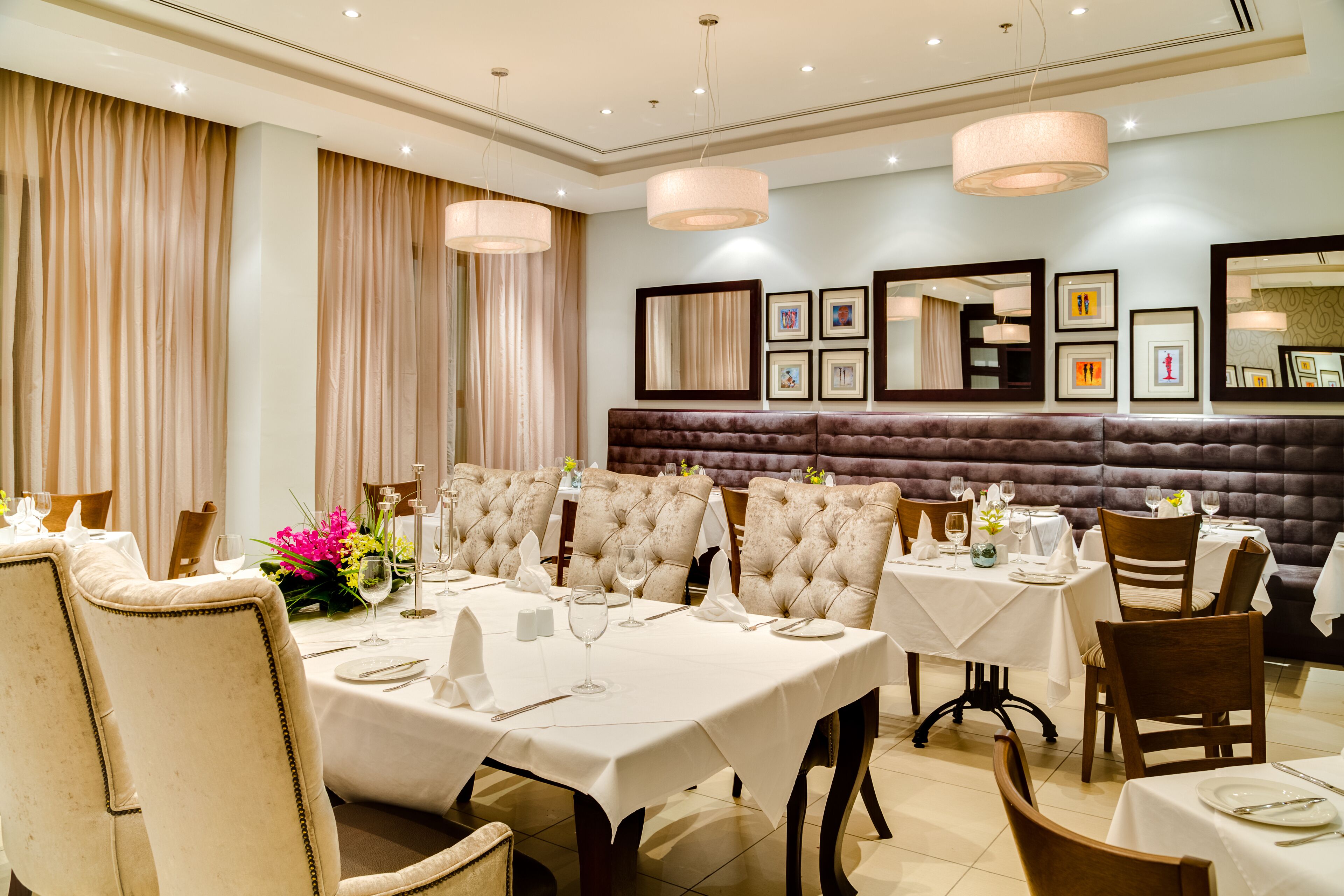 Un comedor formal con varias mesas, sillas tapizadas e iluminación elegante.