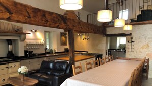 Una cocina amplia con una larga mesa de comedor, un sofá de cuero y sillas de madera.