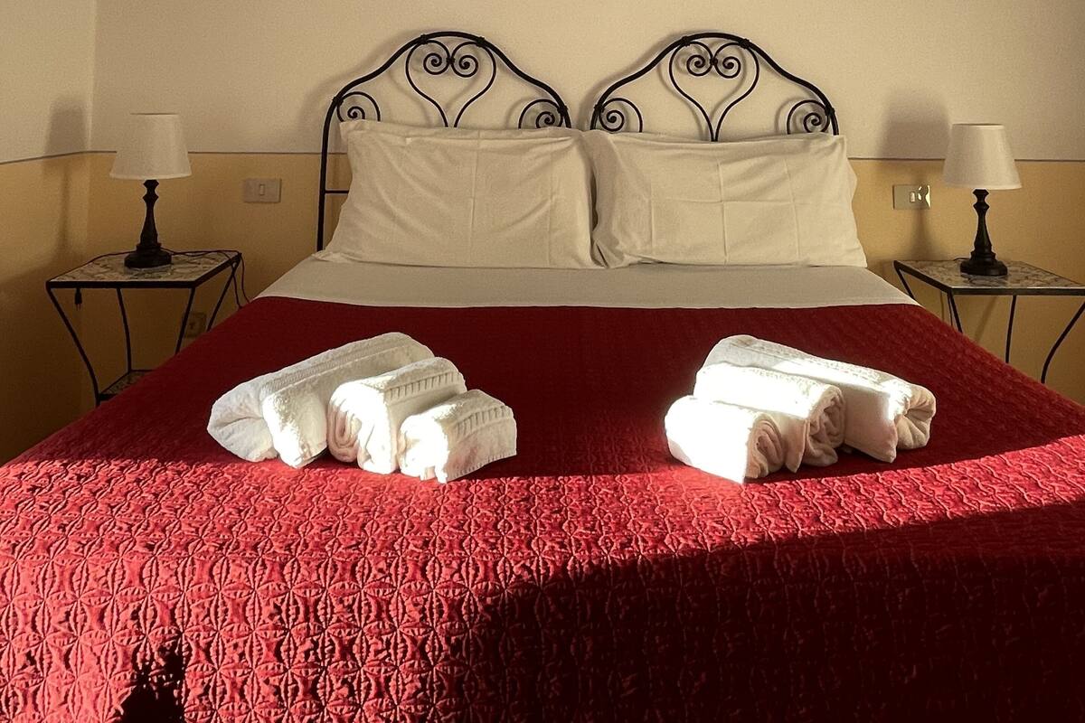 A hotel room with a bed, two bedside tables, and a wall-mounted artwork.