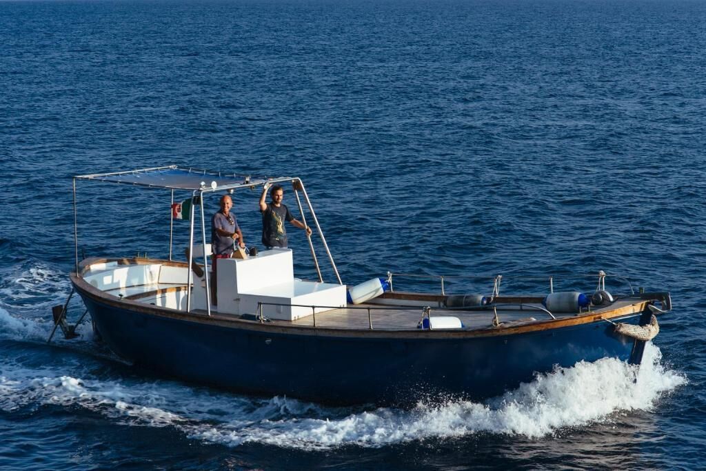 Um pequeno barco a motor com duas pessoas a bordo, navegando em águas.