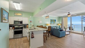 A spacious living area with a kitchen, dining space, and a balcony with a view. - 2BR/2BA, Amazing Gulf/Pool Views! Shores of Panama (Panama City Beach)