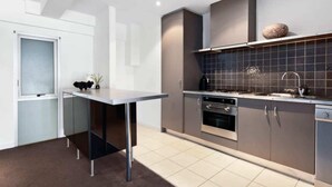 A modern kitchen with grey cabinets, a stainless steel stove, and a tiled backsplash. - Light-filled Converted Warehouse 2 Bedroom Apartment in Prahran (Prahran)