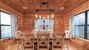 A wooden cabin interior with a dining table, four chairs, and large windows with checkered curtains. - Private Mountain Cabin to Gather, Relax & Unwind near Pigeon Forge,TN (Sevierville)