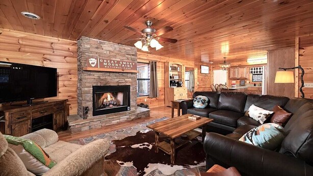 A log cabin interior with a stone fireplace, leather furniture, and a television. - Private Mountain Cabin to Gather, Relax & Unwind near Pigeon Forge,TN (Sevierville)