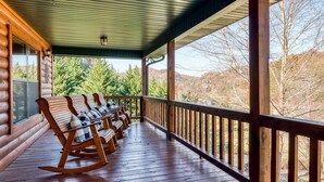 A wooden porch with rocking chairs and a view of a forested landscape. - Private Mountain Cabin to Gather, Relax & Unwind near Pigeon Forge,TN (Sevierville)