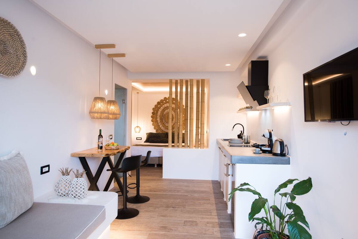 Una cocina moderna con comedor, un sofá y un televisor colgado en la pared.