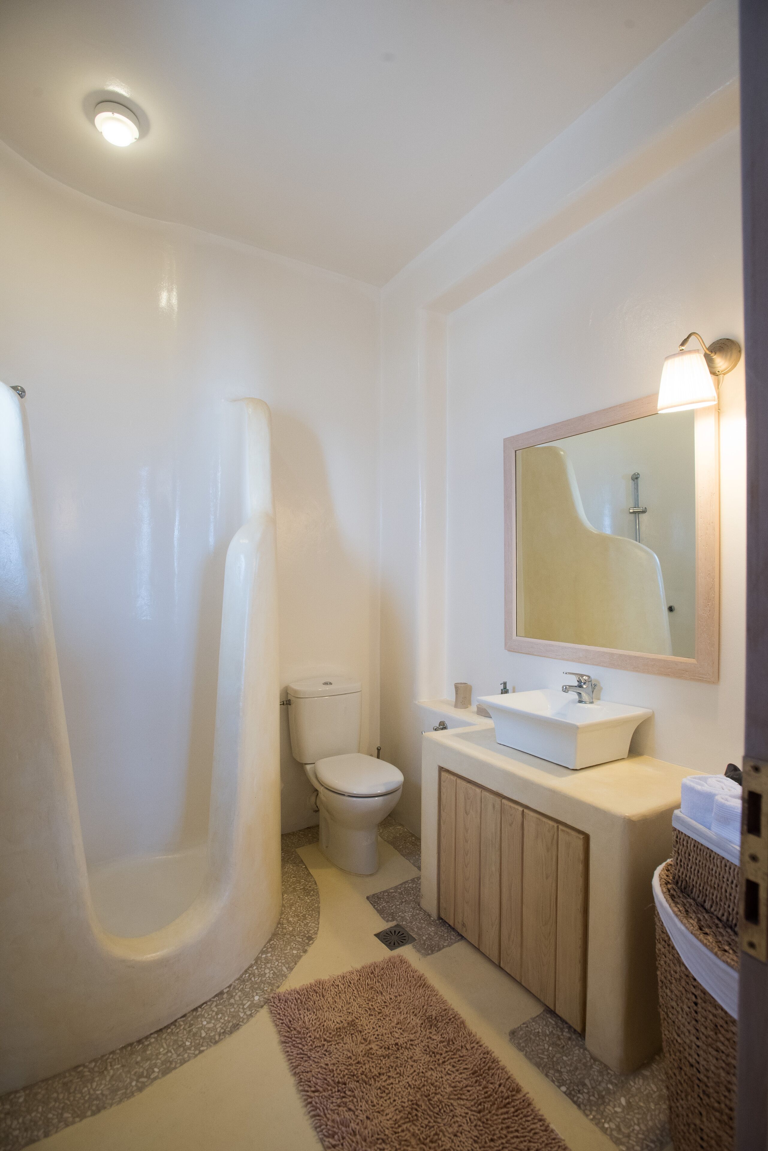 A bathroom with a bathtub, toilet, sink, and a mirror with a light.