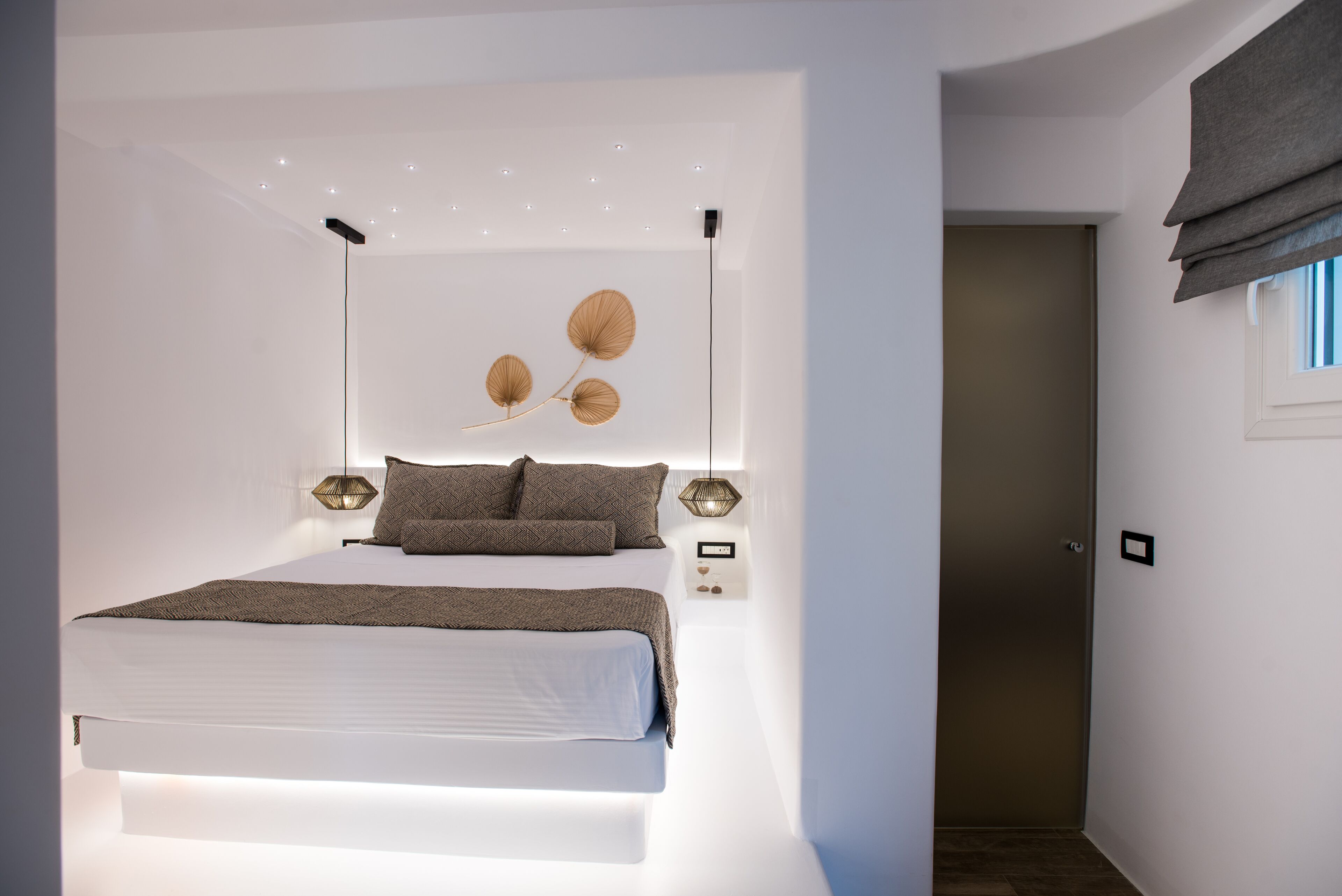 Un dormitorio moderno con una cama grande, iluminación montada en la pared y un elemento decorativo en la pared.