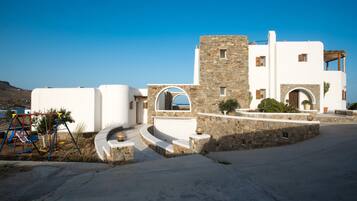 Un edificio blanco con detalles de piedra, una escalera de piedra y un arenero.
