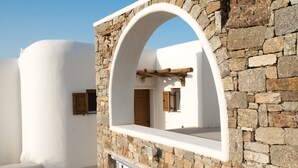 A stone wall with a white archway leading to a room. - Case di Venia (Mykonos)