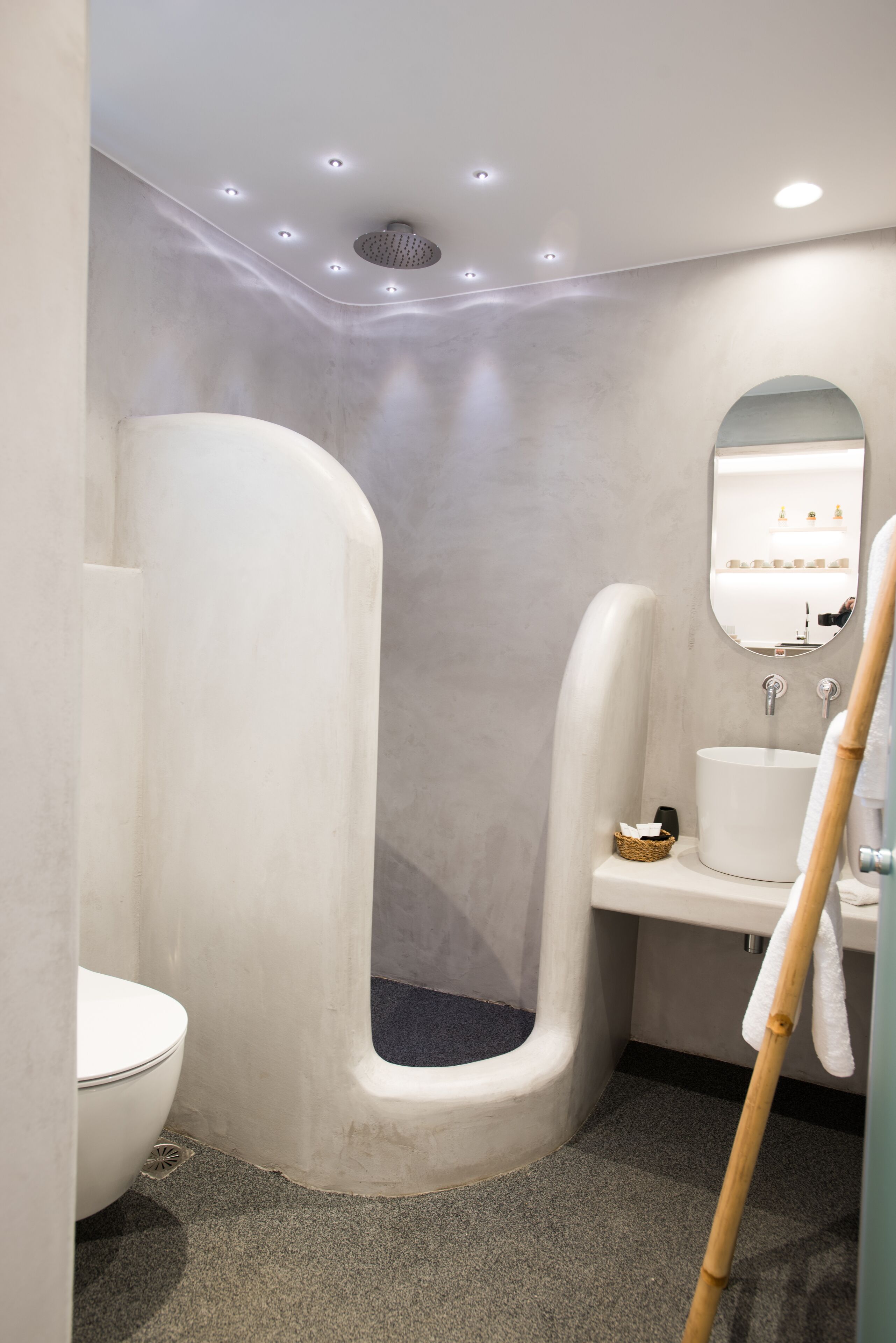 A modern bathroom with a curved shower, a white sink, and a mirror above it.