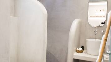 A modern bathroom with a curved shower, a white sink, and a mirror above it.