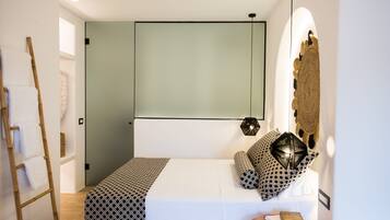 A modern bedroom with a bed, a wooden ladder, a wall-mounted light, and a decorative wall piece.