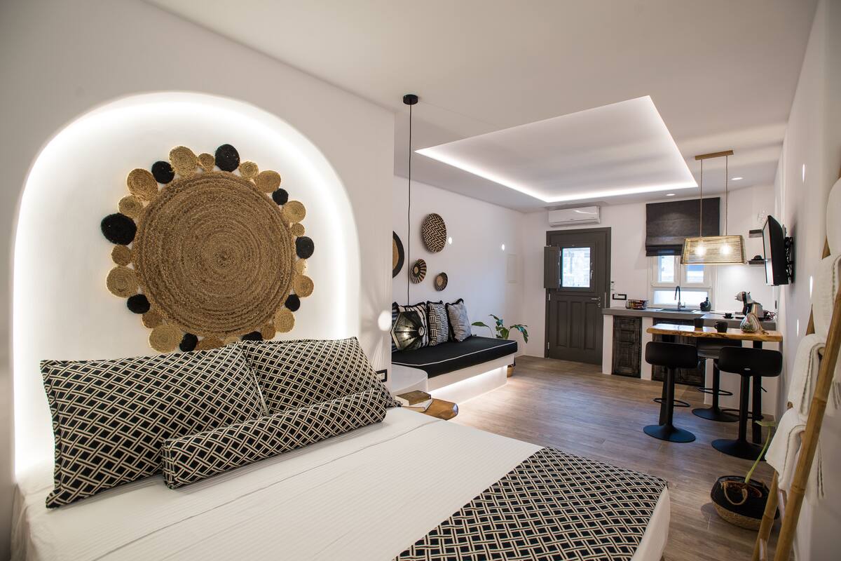 Una sala de estar moderna con un sofá, una zona de comedor y una cocina al fondo, además de una decoración circular única en la pared.