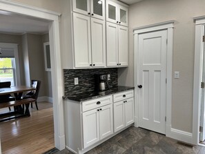 A kitchen with white cabinets, a black countertop, and a tiled backsplash.