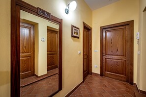 Un pasillo con puertas de madera, un aplique en la pared y un pequeño cuadro enmarcado.
